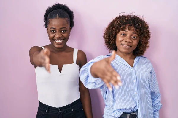 Duas Mulheres Africanas Sobre Fundo Rosa Sorrindo Amigável Oferecendo Aperto — Fotografia de Stock