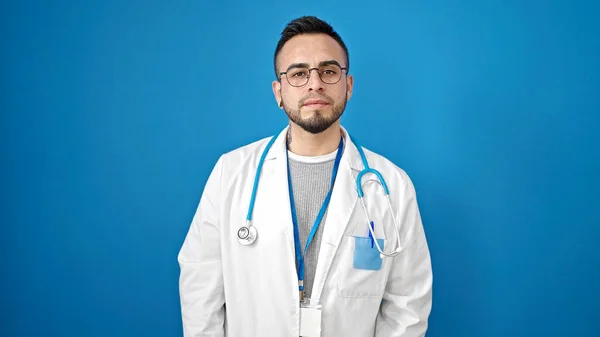 Latynoski Lekarz Stojący Poważnym Wyrazem Twarzy Odizolowanym Niebieskim Tle — Zdjęcie stockowe