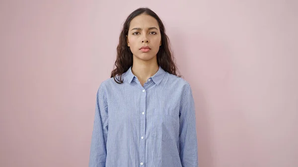 stock image Young beautiful hispanic woman standing with serious expression over isolated pink background