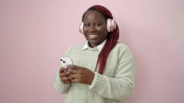 Африканская Женщина Плетеными Волосами Помощью Смартфона Наушниках Изолированном Розовом Фоне — стоковое фото