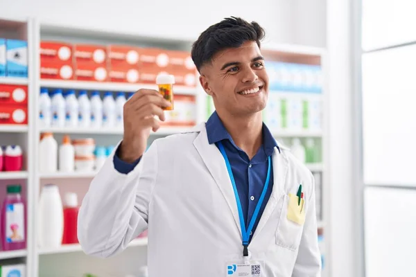 Young Hispanic Man Pharmacist Smiling Confident Holding Pills Bottle Pharmacy — Zdjęcie stockowe