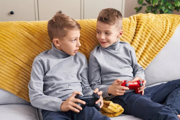 可爱的男孩子们坐在家里的沙发上玩电子游戏 — 图库照片