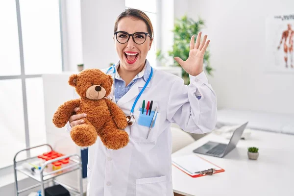 Young Hispanic Pediatrician Woman Holding Teddy Bear Clinic Celebrating Victory — Stock Photo, Image
