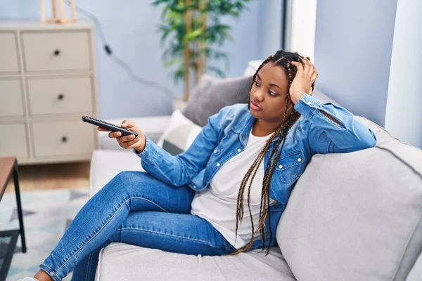 Африканская Американка Смотрит Телевизор Сидя Диване Скучным Выражением Лица Дома — стоковое фото