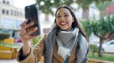 Genç, güzel, İspanyol bir kadın, gülümsüyor. Parkta kendine güvenen bir video var.