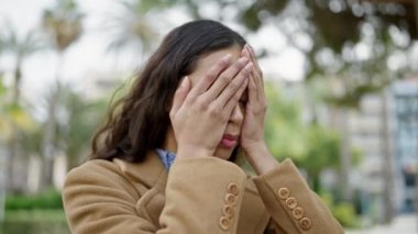 Parkta yüzünde stresli bir ifadeyle duran genç, güzel İspanyol kadın.