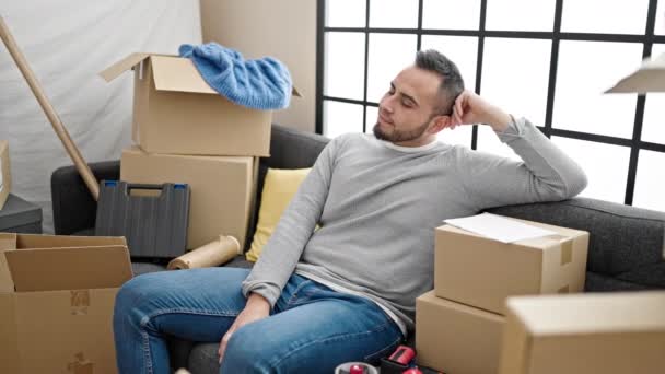 Hispanic Man Sitting Sofa Stretching Arms New Home — Stock Video