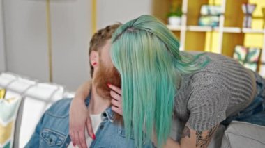 Erkek ve kadın çift birbirlerine sarılıyorlar koltukta oturmuş evde öpüşüyorlar.