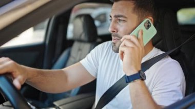 Genç İspanyol adam akıllı telefondan konuşuyor. Sokakta kazanan yüz ifadesiyle arabada oturuyor.