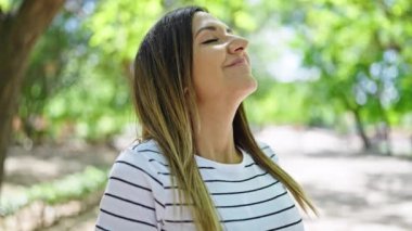 Ortadoğulu kadın parkta kendine güvenen bir şekilde gülümsüyor.