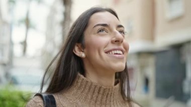 Young beautiful hispanic woman smiling confident looking to the sky at street
