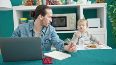 Baba ve oğul yemek odasında çalışıyor ve çocuğa bakıyor.