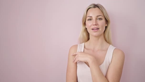 Молода Блондинка Посміхається Вказуючи Бік Ізольованого Рожевого Фону — стокове відео