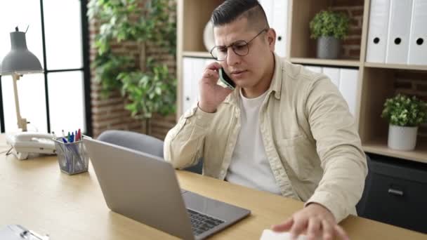 Young Hispanic Man Business Worker Using Laptop Talking Smartphone Office — Stok video
