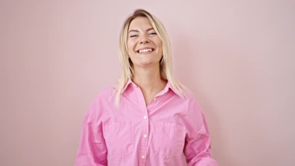 年轻的金发女人带着大拇指对着孤立的粉色背景微笑 — 图库视频影像