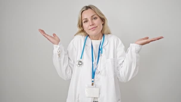 若いですブロンド女性医師立っていますClueless上の隔離された白い背景 — ストック動画