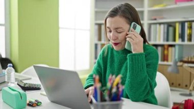 Kütüphanede bilgisayarla konuşan gri saçlı, olgun İspanyol bir kadın.