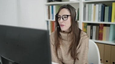 Güzel İspanyol bayan öğrenci kütüphane üniversitesinde video araması yaptığından emin bir şekilde gülümsüyor.