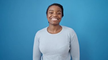 İzole edilmiş mavi arka planda gülümseyen Afrikalı Amerikalı kadın.