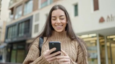 Sokakta gülümseyen akıllı telefon kullanan genç, güzel İspanyol kadın.