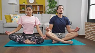 Erkek ve kadın çift evde yoga egzersizi yapıyor.