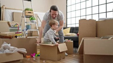 Baba ve oğul yeni evlerinde karton kutularla oynuyorlar.