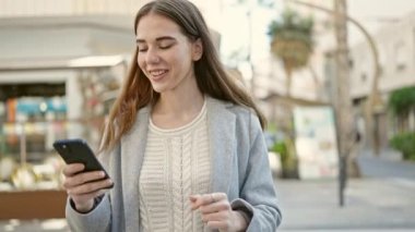 Genç İspanyol kadın dans ediyor, kafenin terasında akıllı telefondan müzik dinliyor.