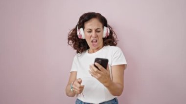 Orta yaşlı İspanyol bir kadın müzik dinliyor. Pembe arka planda gitar jesti yapıyor.