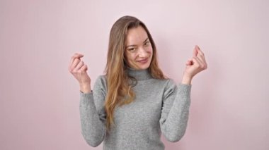 Kafkasyalı genç bir kadın kendine güvenerek gülümsüyor. Soyutlanmış pembe arka planda para harcıyor.