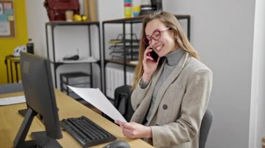 Kafkasyalı genç bir iş kadını ofisteki akıllı telefon okuma belgeleriyle konuşuyor.