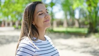 Ortadoğulu kadın parkta kendinden emin gülümsüyor.