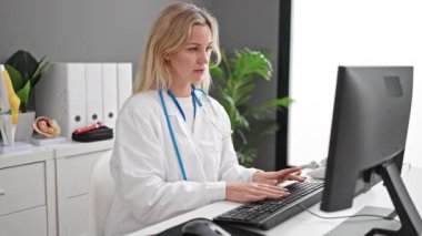 Klinikte bilgisayar kullanan genç sarışın kadın doktor.