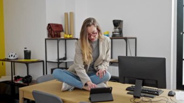 Kafkasyalı genç iş kadını yoga egzersizi yapıyor. Ofiste masada oturuyor.