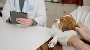 Veteriner kliniğinde dokunmatik ped kullanan iki adam.