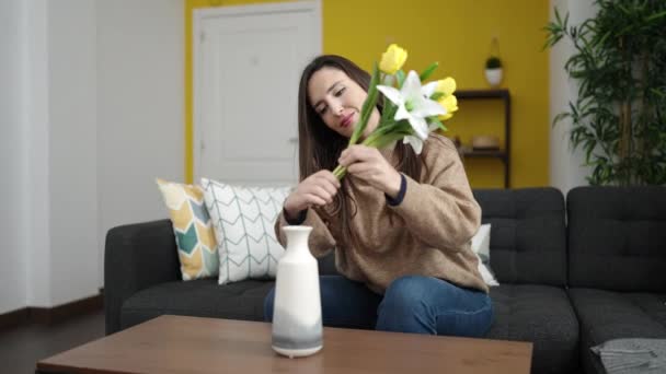 漂亮的惊慌失措的女人把花放在家里沙发上的花瓶里 — 图库视频影像