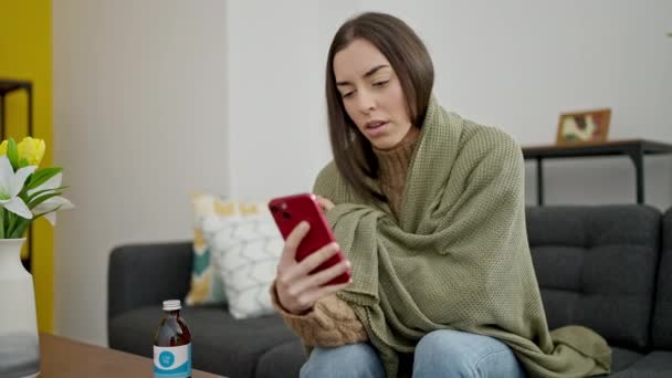 年轻美丽的惊慌失措的女人用智能手机在家里咳嗽 — 图库视频影像