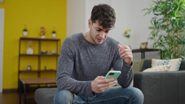 Jovem Hispânico Usando Smartphone Preocupado Sentado Sofá Casa — Vídeo de Stock