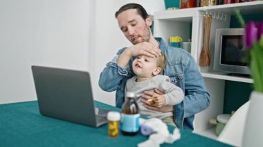 Baba ve oğul yemek odasında online tıbbi danışmanlık yapıyorlar.