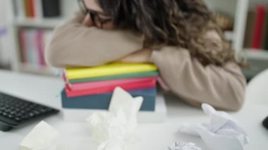 Kitapların üzerinde kafa sallayarak uyuyan genç, güzel İspanyol kadın öğrenci kütüphanede uyanıyor.