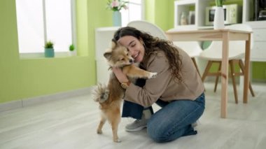 Köpekli genç İspanyol kadın yemek odasında yerde oturmuş sarılıyor.