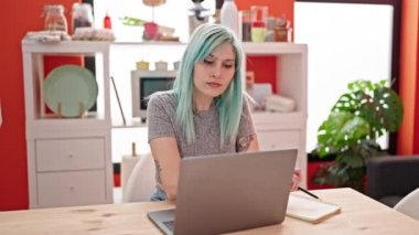 Kadın ve erkek yemek odasında dizüstü bilgisayar kullanarak ellerinde kahve tutuyorlar.