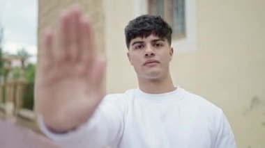Genç İspanyol adam sokakta el hareketlerini durduruyor.