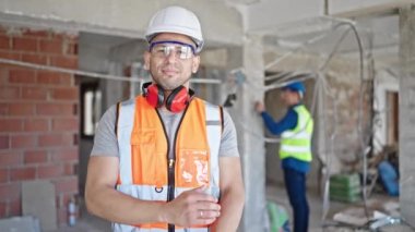 İnşaat alanında çalışan iki inşaatçı kollarını kavuşturmuş.
