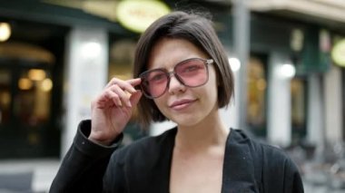 Sokakta kendine güvenen beyaz kadın gülümsüyor.