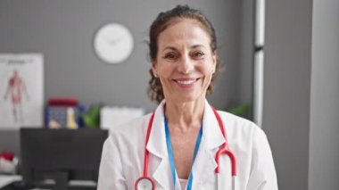 Klinikte kendine gülen orta yaşlı İspanyol kadın doktor.