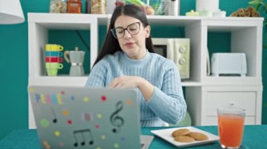 Genç İspanyol kadın yemek odasında laptopunu kullanıyor.