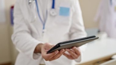 Genç İspanyol doktor klinikte dokunmatik ped kullanıyor.