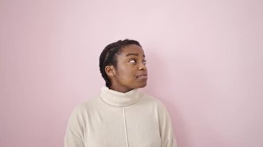 Beklenmedik bir ifadeyle afro-amerikalı kadın pembe arka plana bakıyor.