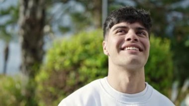 Parkta kendinden emin gülümseyen İspanyol genç adam.