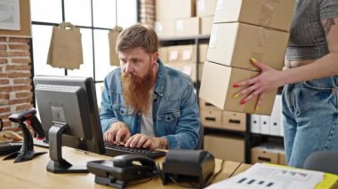 Erkek ve kadın ecommerce işçileri ofislerinde bilgisayar paketlerini kullanıyorlar.